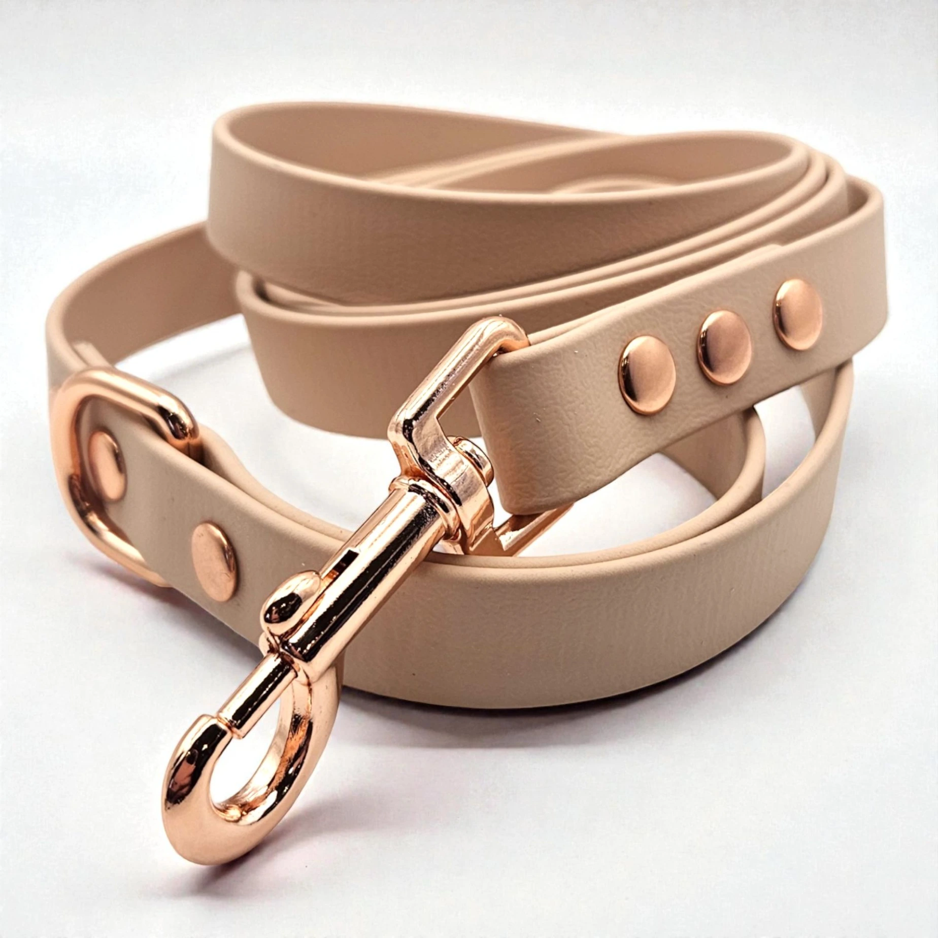 Close-up studio shot of The Classic Lead in Cotton Tail, a beige BioThane dog lead with elegant rose gold hardware on a white background. Bespoke, easy-to-clean dog gear for stylish adventures.