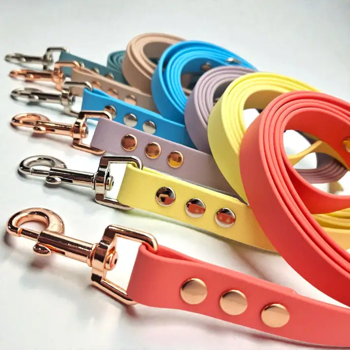 A collection of handcrafted dog leads made from premium BioThane®, featuring pastel colours such as peach, yellow, lilac, blue, and taupe. Sturdy rose gold hardware and rivets add durability and style. Waterproof, stink-proof, and easy to clean. Ideal for animal lovers who appreciate both functionality and vibrant design.
