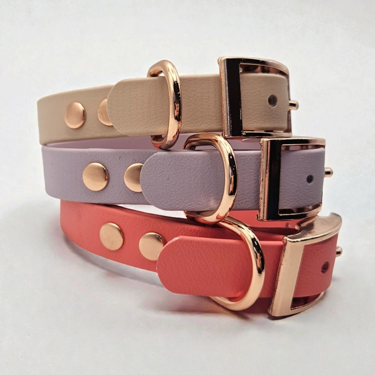 Three handcrafted BioThane® dog collars in pastel cream, lilac, and coral, each featuring rose gold-toned buckles and hardware. These waterproof, stink-proof collars from Ponies &amp; Pups are durable, easy to clean, and customisable in colour and size, perfect for stylish, practical pet owners.