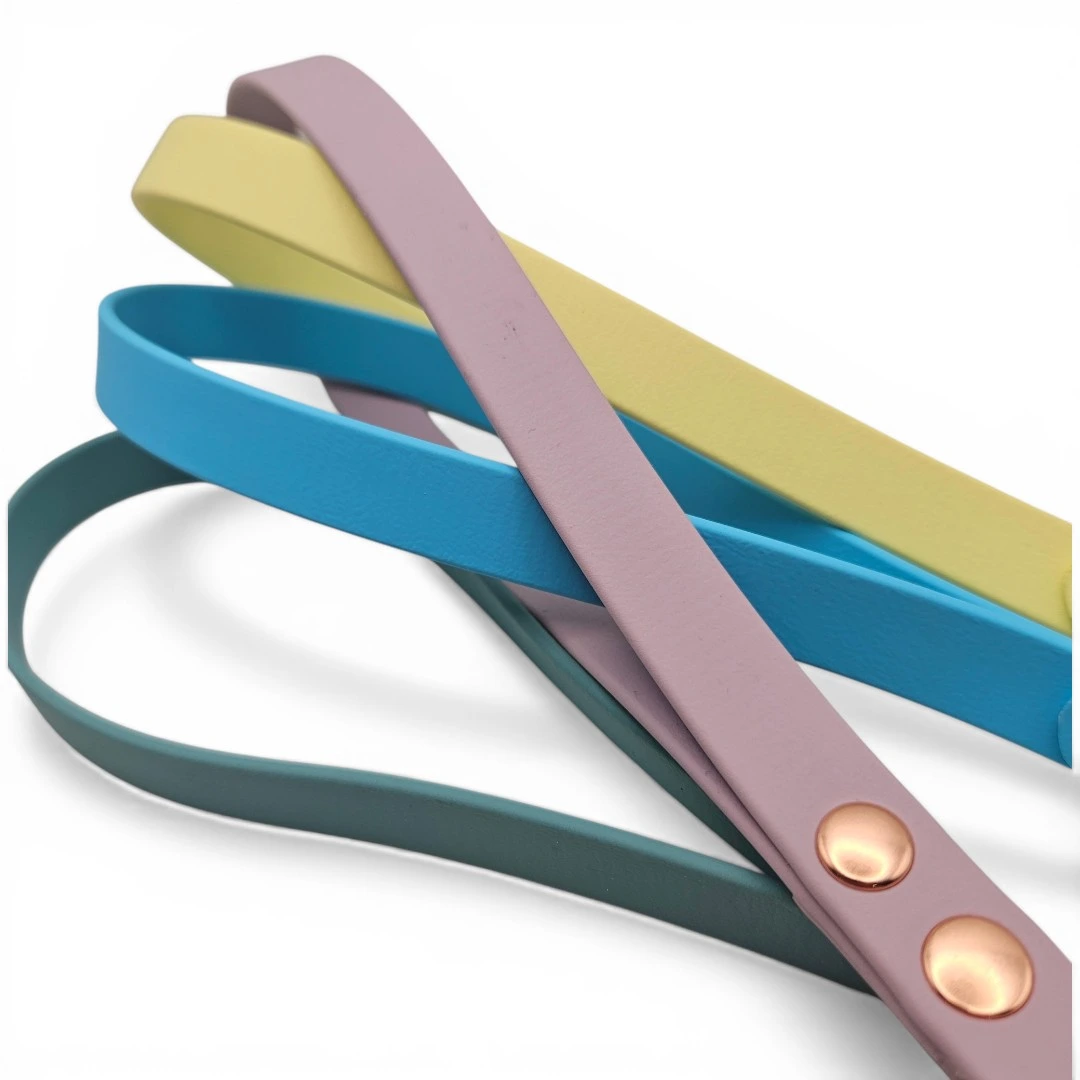Four handcrafted BioThane® dog leads in pastel yellow, mauve, teal, and blue. Each is finished with copper hardware, waterproof and odour-proof, showcasing bespoke, colourful options for stylish and durable pet gear.